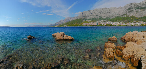 Panoramic view of the turquoise water of the Adriatic Sea and the town of Makarska, Croatia, with the Biokovo mountain in sunny summer day