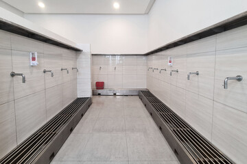 Modern ablution or wudu room with clean design, minimalist silver water taps and tiled walls before...