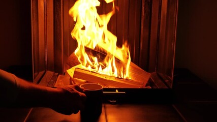 Tea by the fireplace. A hand places a glass of tea next to a glass fireplace. A cozy video featuring a glass fireplace.