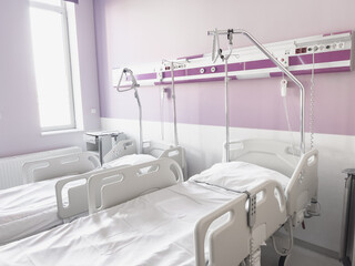 Bright and modern sick room with two empty medical beds in a horizontal orientation, purple walls and natural daylight coming through the window