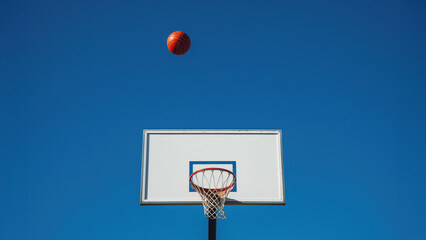 Basketball ball above backboard on deep blue sky. Minimal sports concept.
