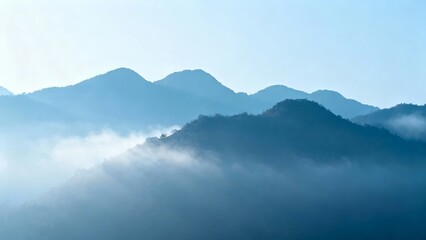 Misty mountain range with layered peaks and fog-covered valleys under a clear blue sky