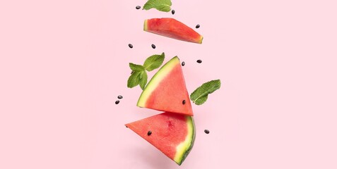 Flying pieces of fresh watermelon, mint and seeds on pink background