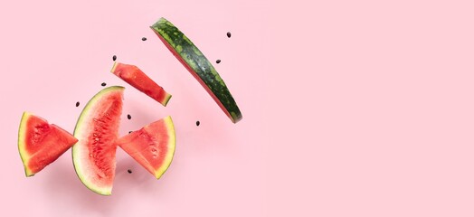 Flying pieces of fresh watermelon and seeds on pink background with space for text