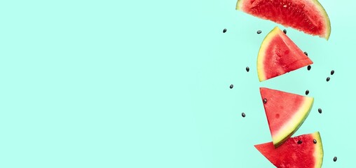 Flying pieces of fresh watermelon and seeds on turquoise background with space for text