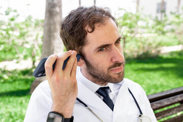 Doctor listening to a voice message outdoors, symbolizing the evolving landscape of telemedicine and remote healthcare services for professional communication and patient access.