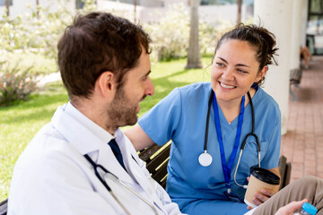 Medical professionals, a doctor and nurse, relaxing together outdoors during a break, sharing a moment of lighthearted conversation and teamwork in a healthcare setting