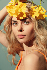 Young woman with floral crown and soft smile in vibrant orange outfit against pastel background