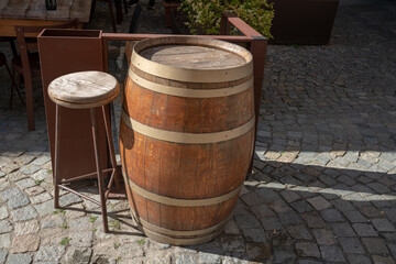 A wooden barrel with a rustic stool in a traditional setting. An authentic atmosphere connected to the production and culture of wine. An artisanal inn reminiscent of cellars, tastings, and tradition.