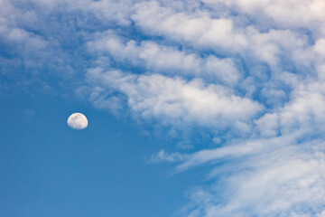 The moon in the blue sky and white clouds on a sunny day