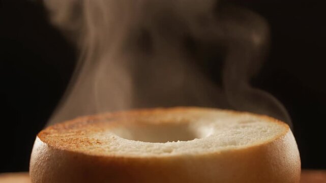Close up of a steaming hot bagel on a wooden surface. 4k Food Footage Video