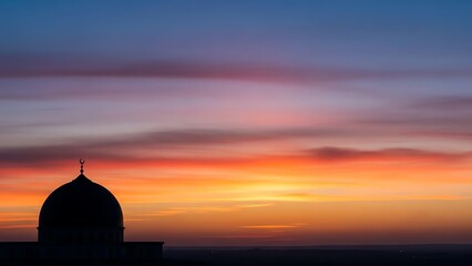 Obraz premium Silhouette of a mosque dome against a vibrant sunset sky.