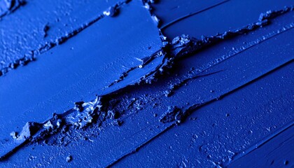 Rich textured abstract background featuring vibrant ultramarine blue pigment swatches with deep grooves and peaks created by a cosmetic or art application tool demonstrating intense color saturation