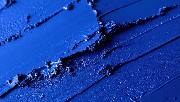 Rich textured abstract background featuring vibrant ultramarine blue pigment swatches with deep grooves and peaks created by a cosmetic or art application tool demonstrating intense color saturation