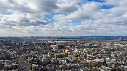 Aerial drone view over Lincoln Park in Jersey City with the Pulaski Skyway stretching across the horizon above the Hackensack River. Surrounding residential neighborhoods, open green space, and waterw
