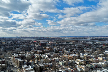 Aerial drone view over Lincoln Park in Jersey City with the Pulaski Skyway stretching across the horizon above the Hackensack River. Surrounding residential neighborhoods, open green space, and waterw