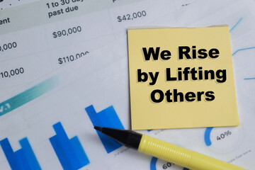 Concept of we rise by lifting others write on sticky notes isolated on Wooden Table.