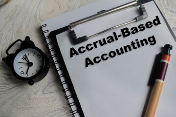 Concept of accrual-based accounting write on clipboard isolated on Wooden Table.