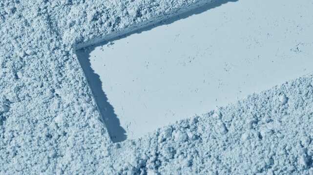 Vertical arc capture of pale blue natural powder surface featuring a dragged rectangular shape pressed in light with orbiting illumination causing moving shadows