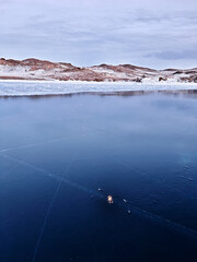 Baikal Lake in winter. Beautiful landscape with mountains reflected in ice of frozen Small Sea