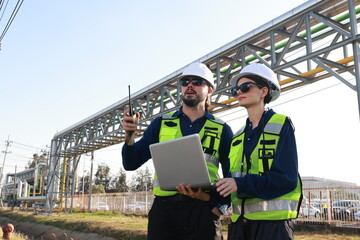 Petrochemical industry night engineer man and woman teamwork working on laptop. Engineer technician working overtime with labtop at refinery construction plant.