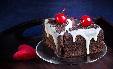 Celebratory chocolate cake with glaze and canned cherry on the wooden tray.