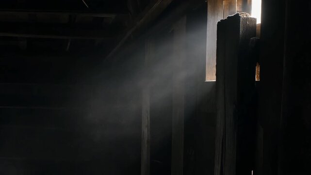 Atmospheric light ray piercing through a dark, dusty room with wooden structures.