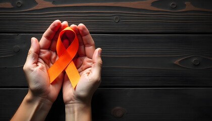 Hands grasping an orange ribbon on a dark wooden surface, highlighting support for kidney cancer awareness and hope