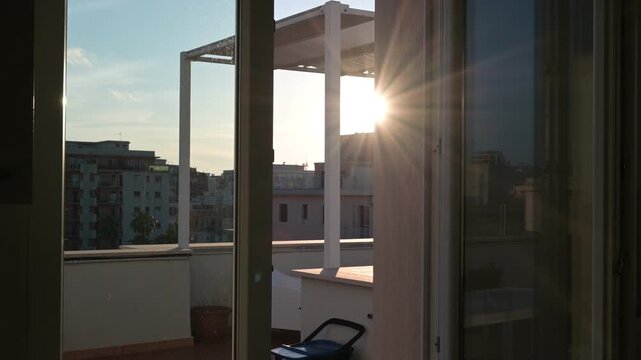 i raggi del sole illuminano un balcone ed entrano in una finestra aperta