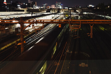 Nighttime train station in Japan with blurred motion of a passing train and city lights