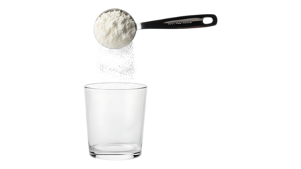 A spoonful of white powder being poured into a clear drinking glass against a black background