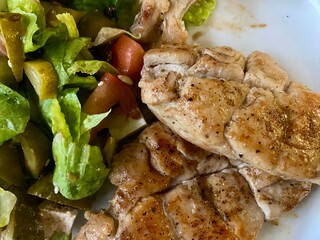 Grilled chicken breasts and a green salad isolated on a plate