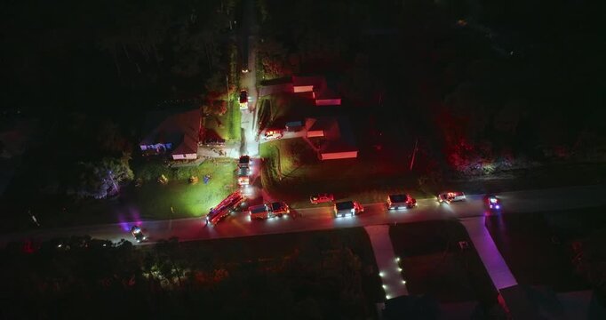 First responders at potential fire hazard at Florida home at night. Firefighter trucks at fire alarm scene of suburban house.
