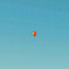 Solitary orange balloon floats high against an endless, clear blue sky