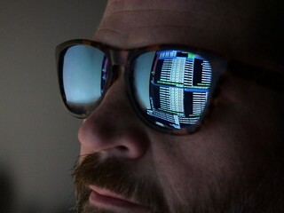 Man Hacking at Terminal Command Prompt Running Networks Scans and Packet Captures - Reflection in Glasses Black Hat Concept
