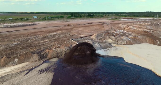 Industrial pipe spraying mixture of water and sediment at mining area, part of phosphate extraction operation in Florida.