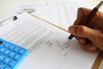An inspection executive giving signature on a inspection report result either it is passed or failed. Business improvement concept. Soft focus. Working paper with documentation, pen and charts. 
