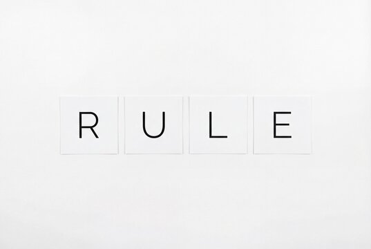 Minimalist flat lay of the word rule spelled on white square cards over white background