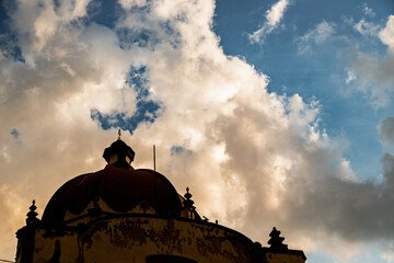 Historic Santa Vera Cruz Temple dome against a dramatic cloudy sky at sunset in Toluca, Mexico
