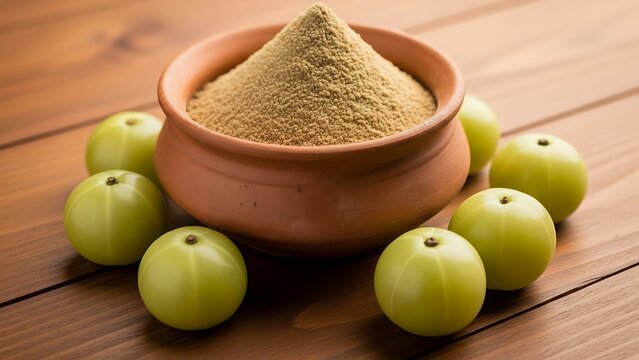 Amla powder in clay bowl surrounded by fresh amla fruits on wooden table. Amla powder for wellness and nutrition content