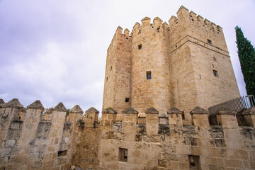View of the historic Calahorra Tower and its medieval stone battlements at the end of the Roman Bridge in Cordoba, Andalusia.