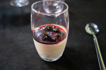 Elegant layered dessert featuring creamy panna cotta topped with dark berry compote, representing refined cuisine along the Don Quixote Route in Spain.
