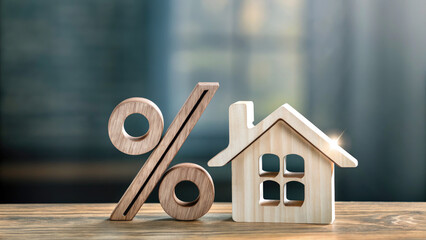 Percentage and wooden house sign symbol concept. Wooden percentage symbol next to a house model on table.