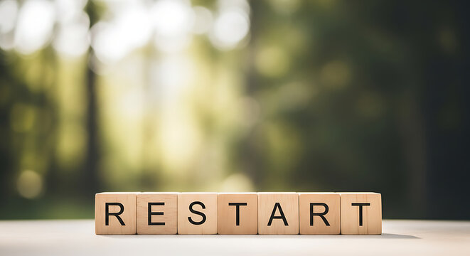 Wooden blocks spelling restart on a table in a serene forest setting with soft natural light