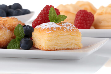Delicious assortment of pastries and berries on a white plate, perfect for a gourmet experience or dessert presentation.