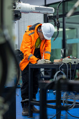 Engineer operating robot arm in electrical industry, Engineer working with robotic equipment...