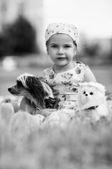 Young girl with braided hair wearing a patterned dress and headscarf is playing with toys on a grassy field, surrounded by colorful play items and a joyful atmosphere