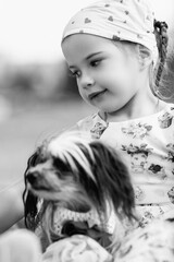 Young girl with braided hair wearing a patterned dress and headscarf is playing with toys on a grassy field, surrounded by colorful play items and a joyful atmosphere