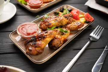 Golden crispy grilled chicken wings served with tomato ketchup on white plate in restaurant