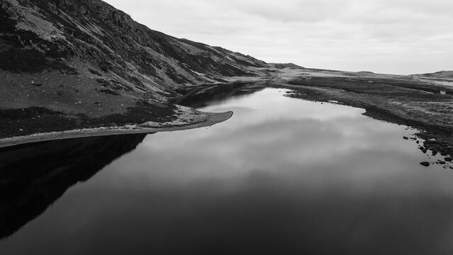 Aerial black and white view of Llyn Eigiau with still water curving beneath steep upland slopes